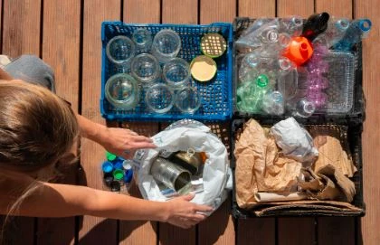 Organização de materiais e objetos recicláveis, incluindo plástico, vidro e papel, sobre uma mesa. Imagem de uma pessoa arrumando lixo reciclável, promovendo práticas sustentáveis.